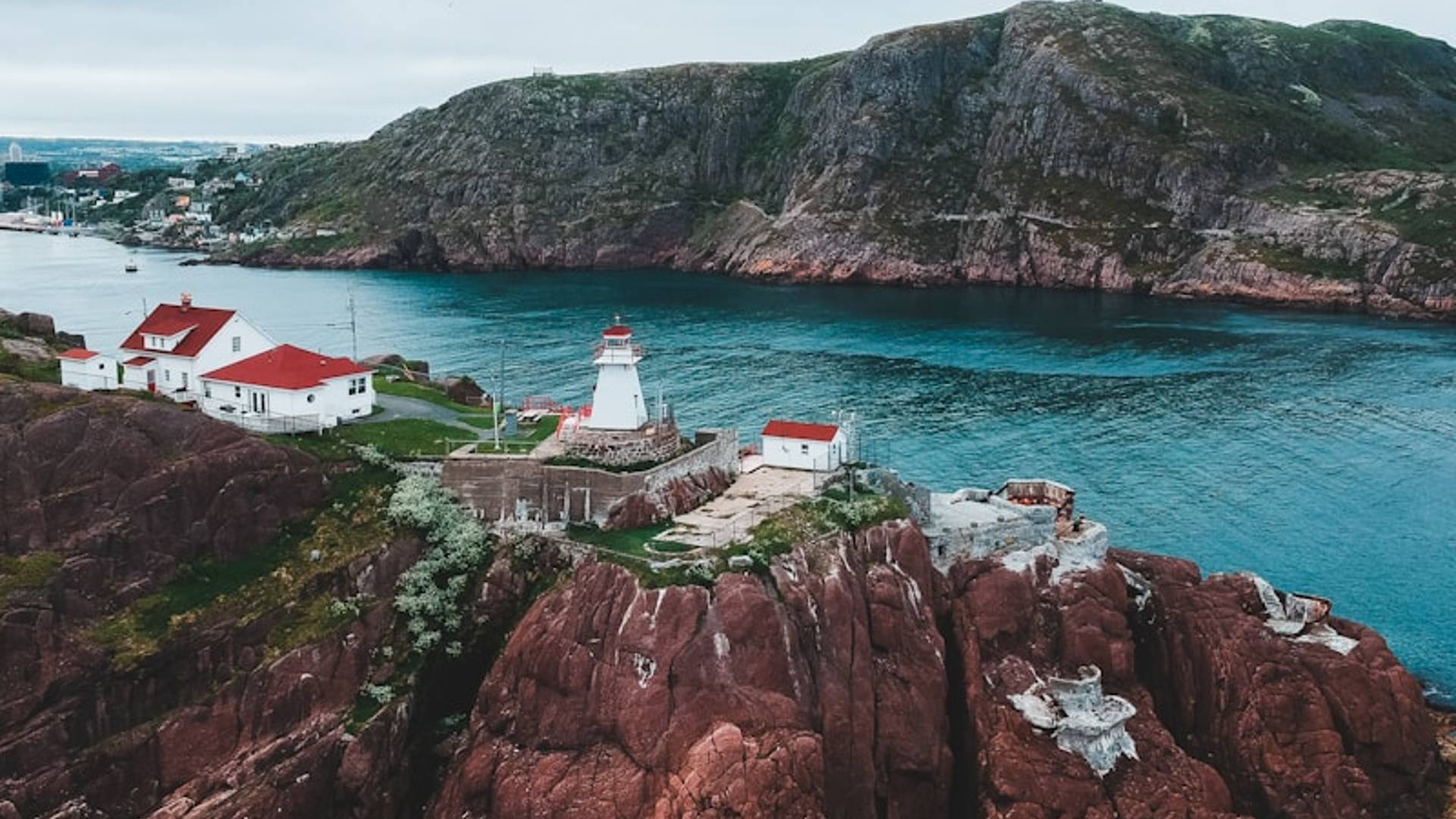 white and red boat on sea near brown and green mountain during daytime