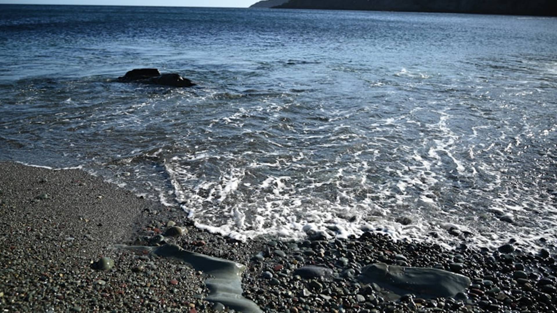 Gentle waves wash over a rocky beach shoreline