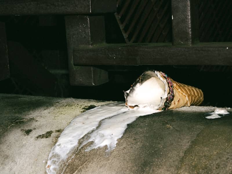 Dropped ice cream cone melting on concrete.