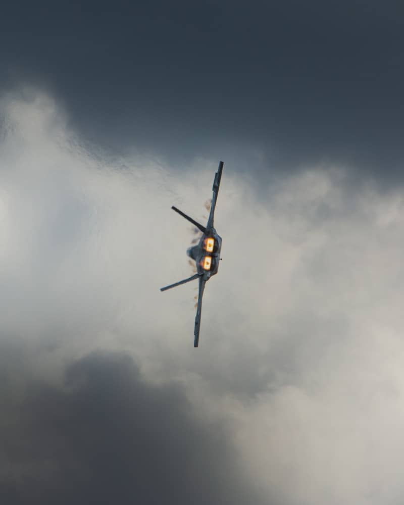 Fighter jet banking sharply against stormy clouds.