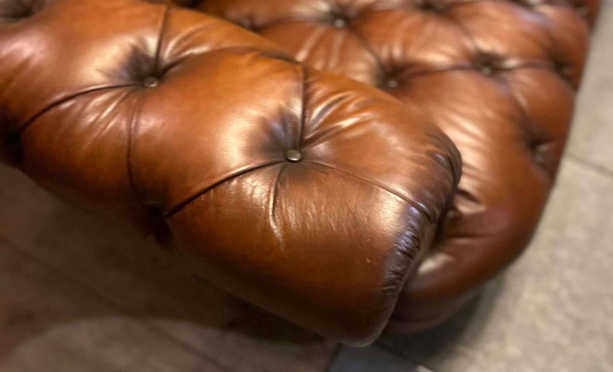 a close up of the arm of a brown leather chesterfield sofa showing the details of the button dimple things