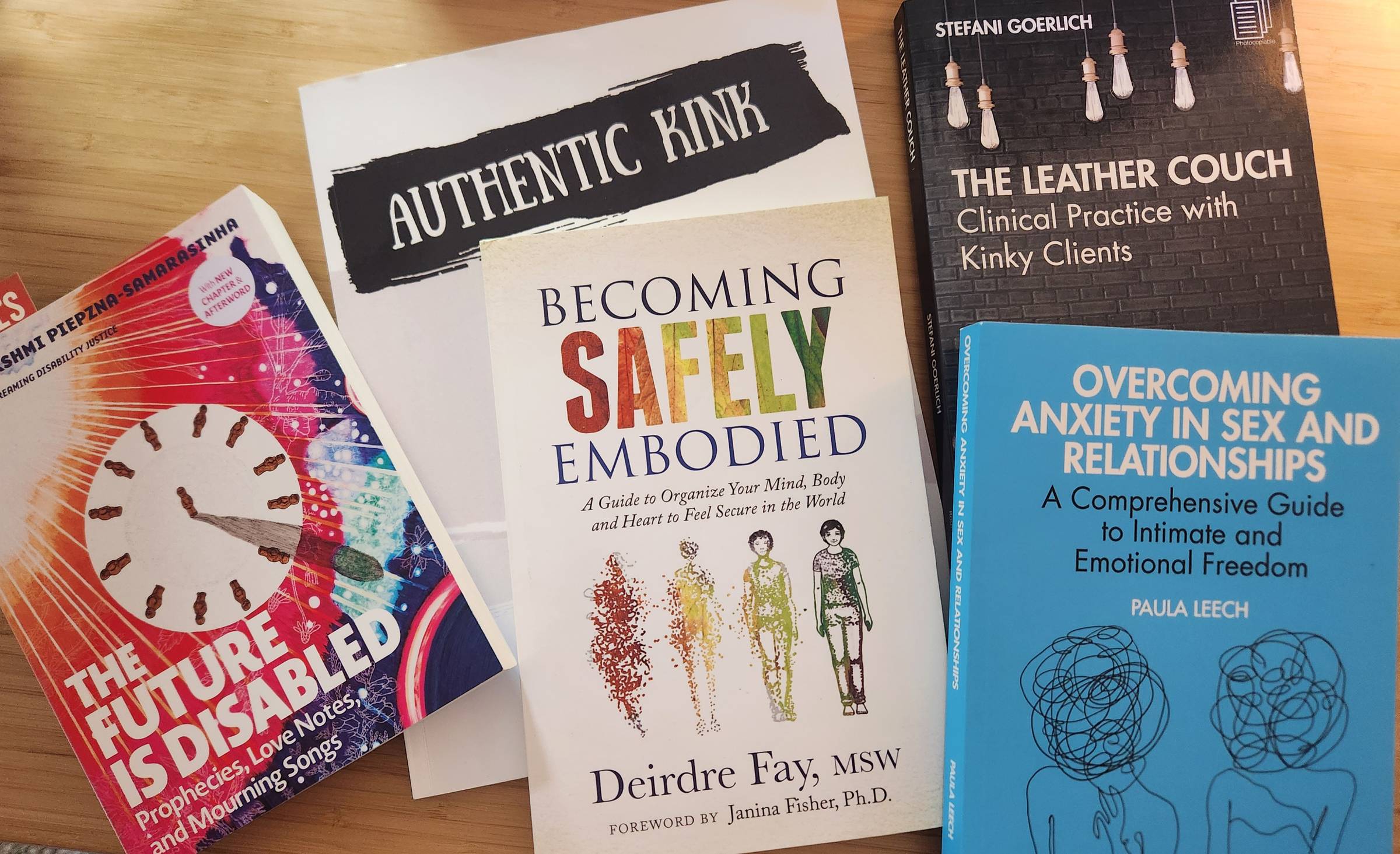 Images of 5 books on a desk: The Future is Disabled; Becoming Safely Embodied; Authentic Kink; The Leather Couch; Overcoming Anxiety in Sex and Relationships