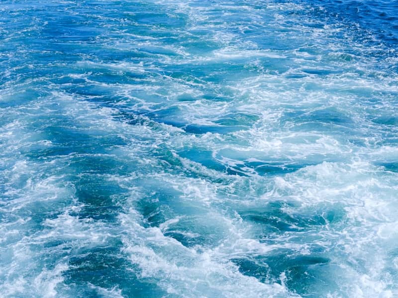 Turbulent blue ocean water with white foam