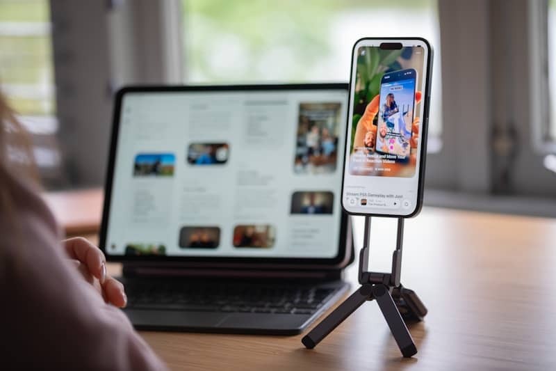 Smartphone on tripod shows social media next to a tablet.