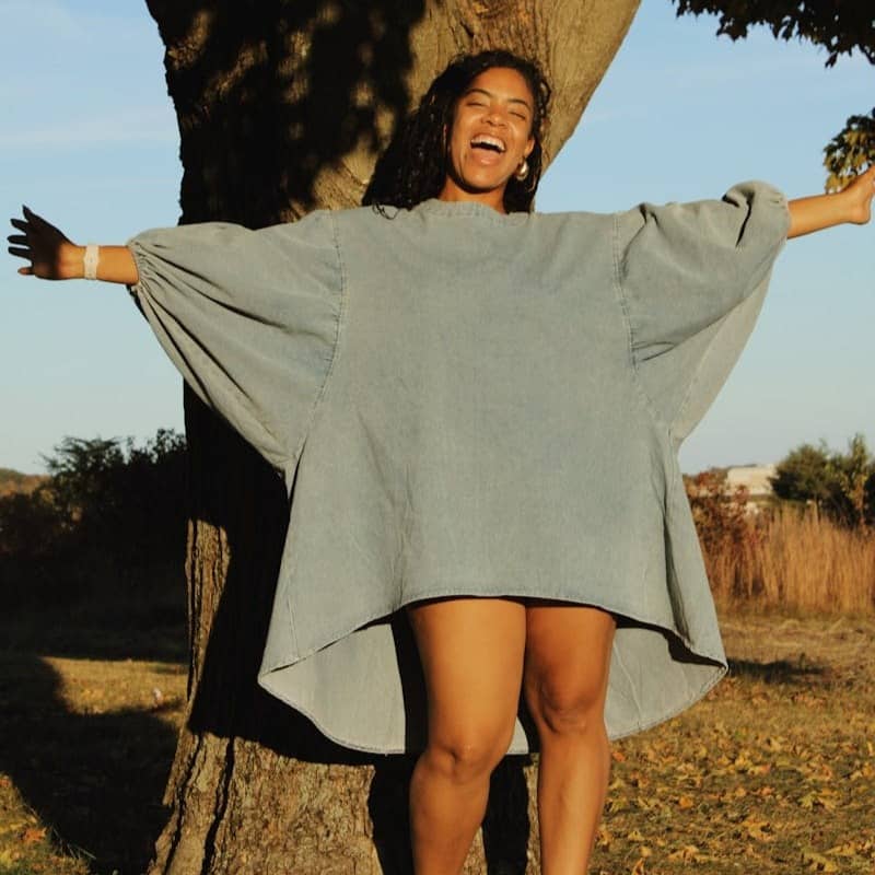 A woman standing in front of a tree with her arms outstretched