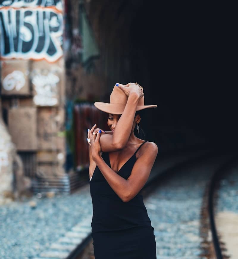 A woman poses by train tracks in a tunnel.