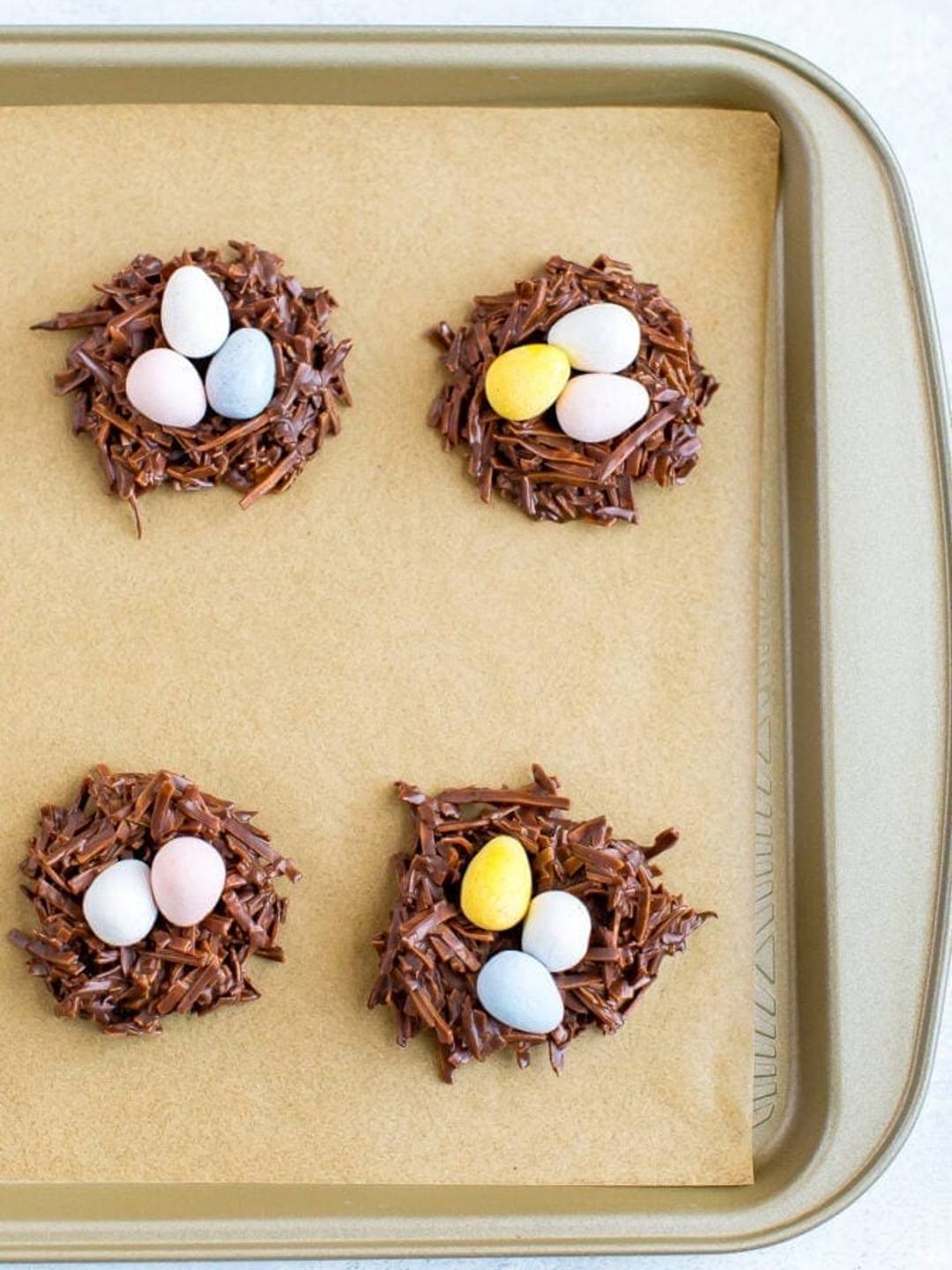 chocolate coconut nests with candy eggs on a baking sheet.