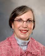 A woman with short brown hair glasses and earrings