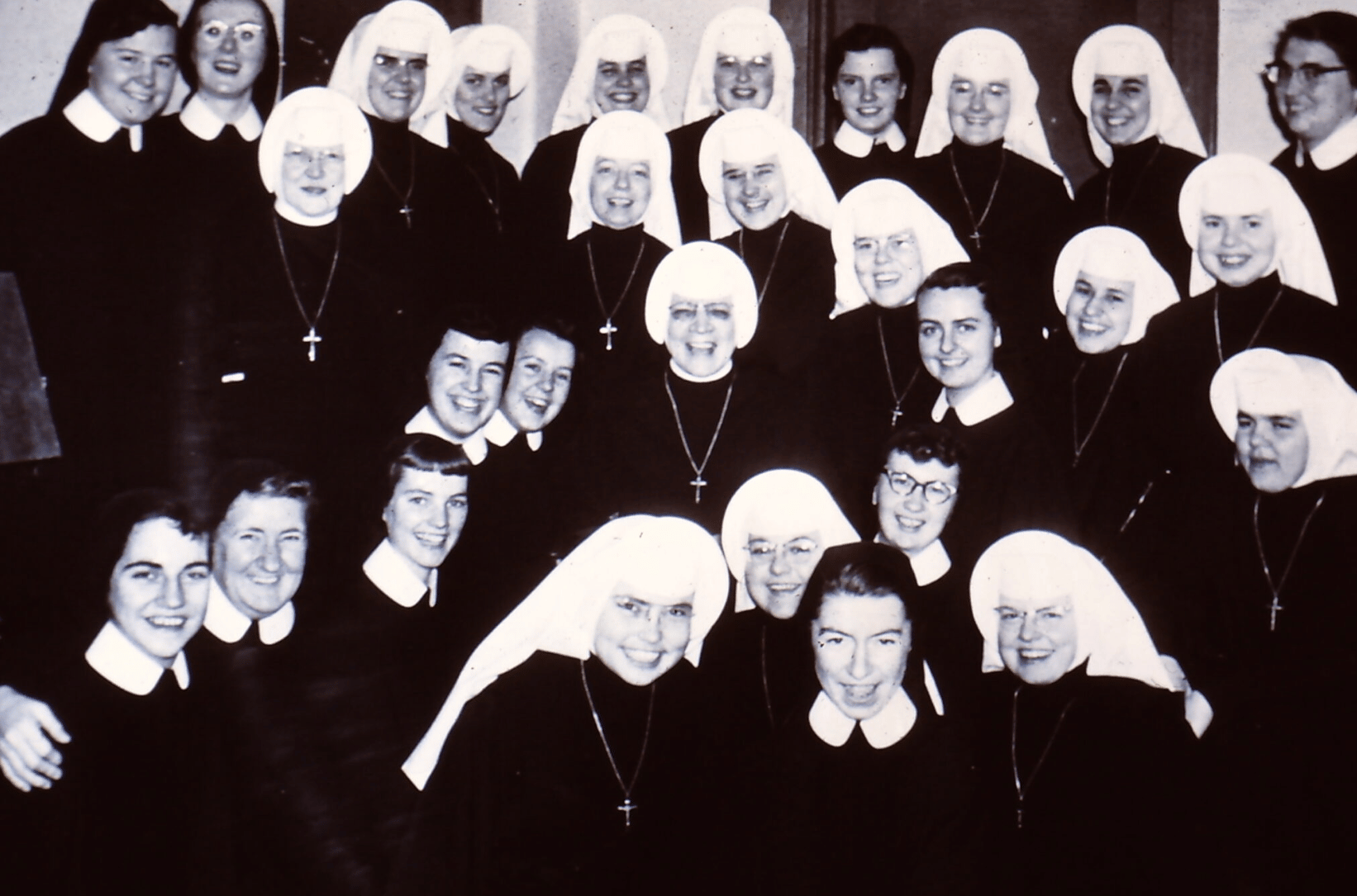 about 25 nuns with white and black veils smiling