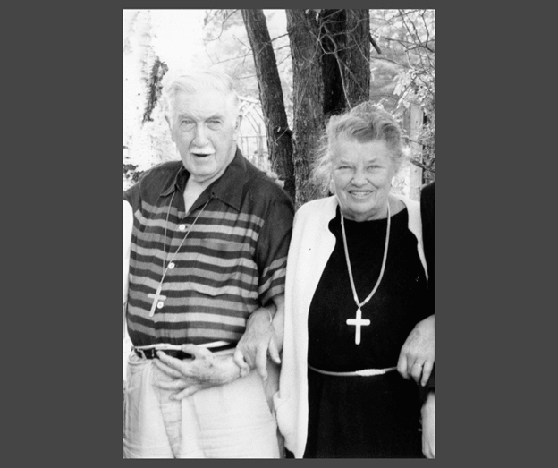 An older man with a mustache next to an older woman, both happy