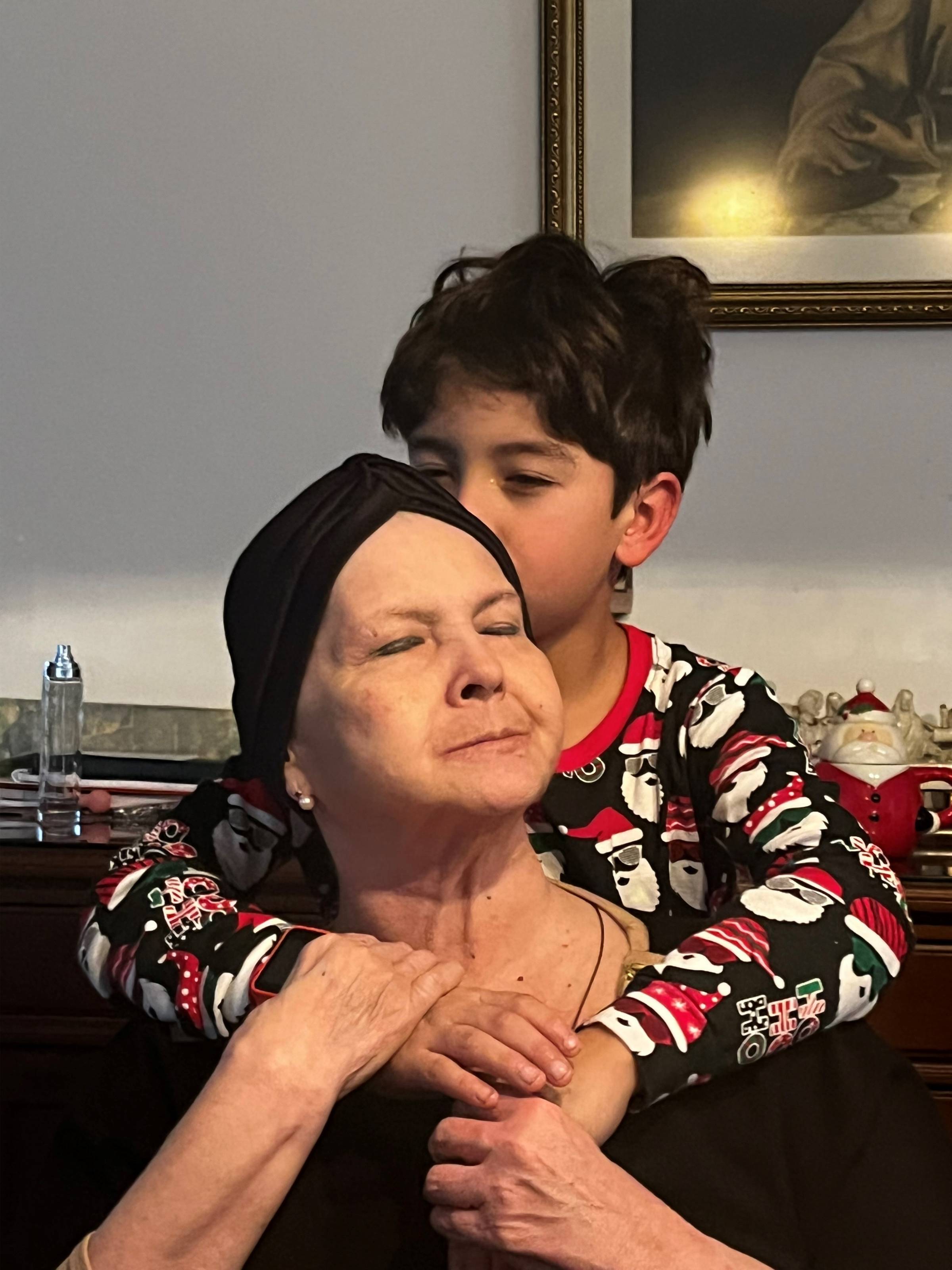 A young boy kissing his grandma, who is wearing a black head covering