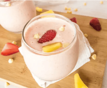 A pink smoothie topped with strawberry and mango