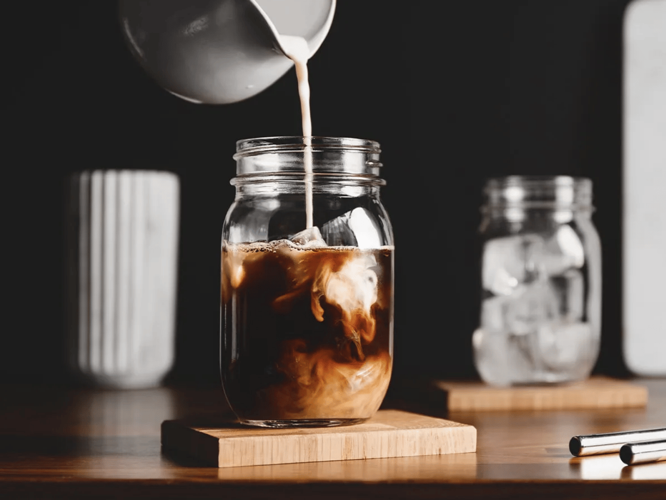 Cream being poured into iced coffee.