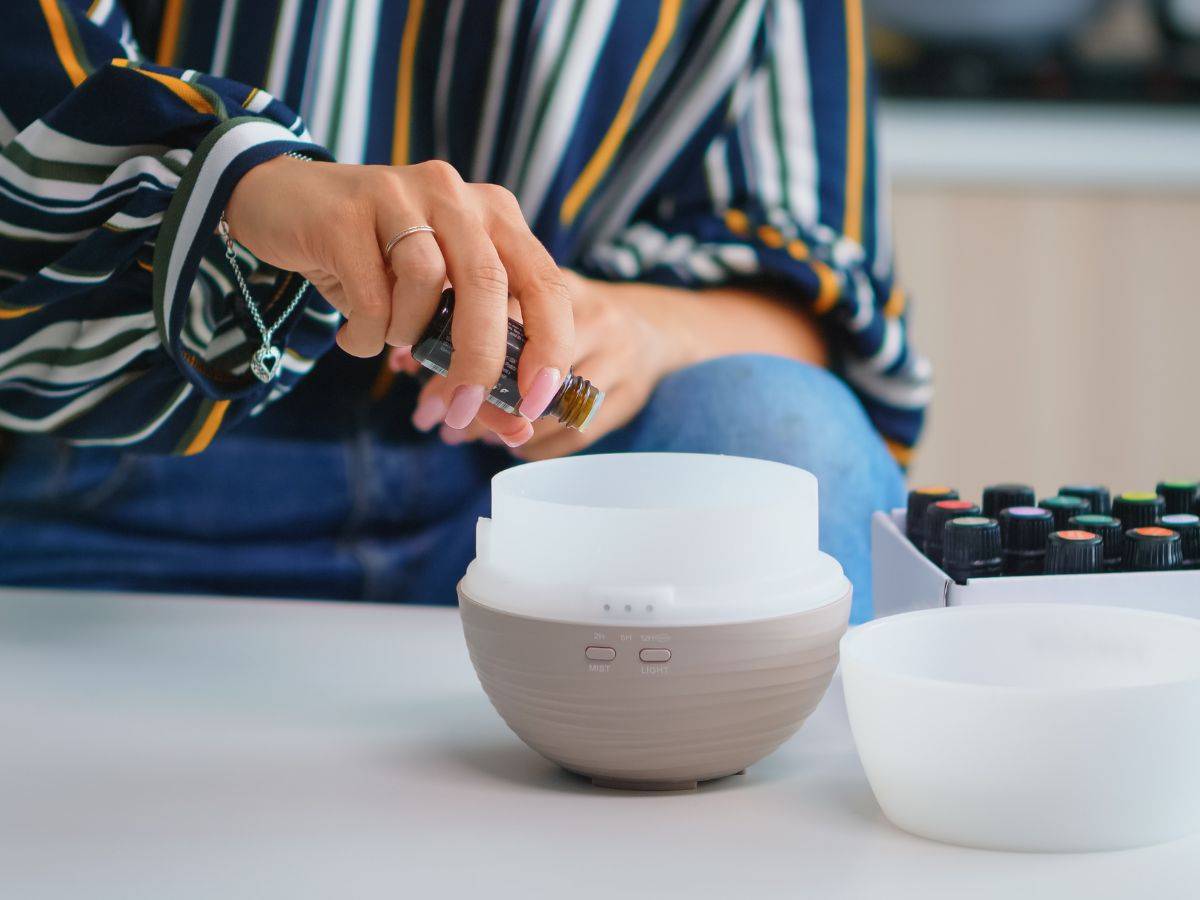 Woman adding drops to an essential oil diffuser.