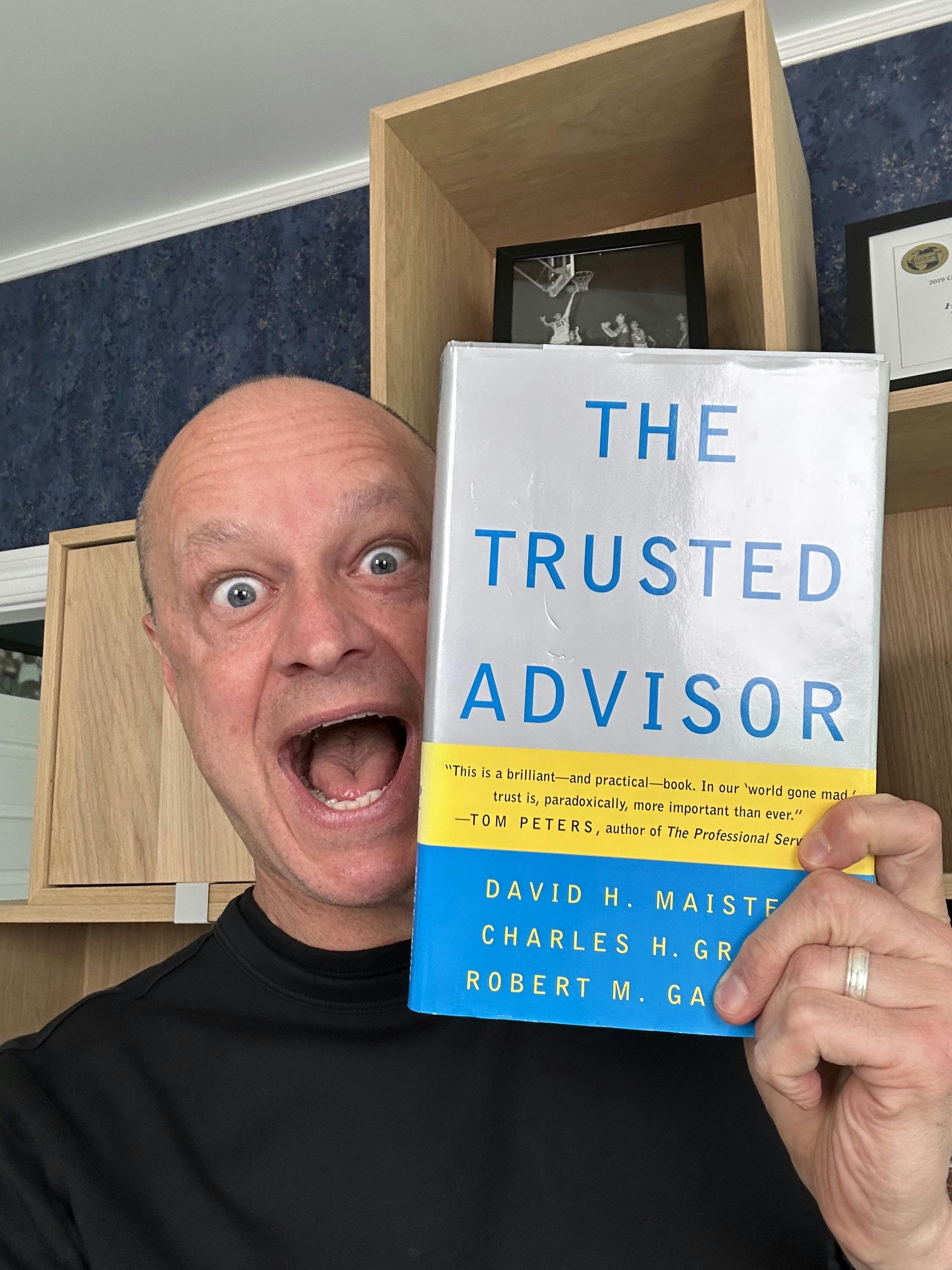 A picture of Mo holding coauthor Charlie Green's book The Trusted Advisor