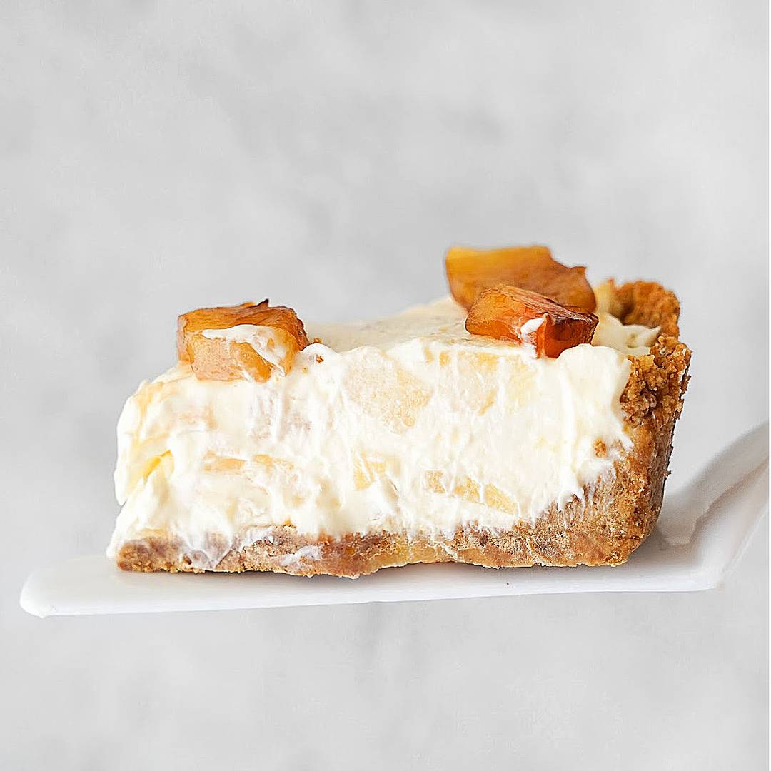 Slice of pineapple cheesecake pie. Light gray background.
