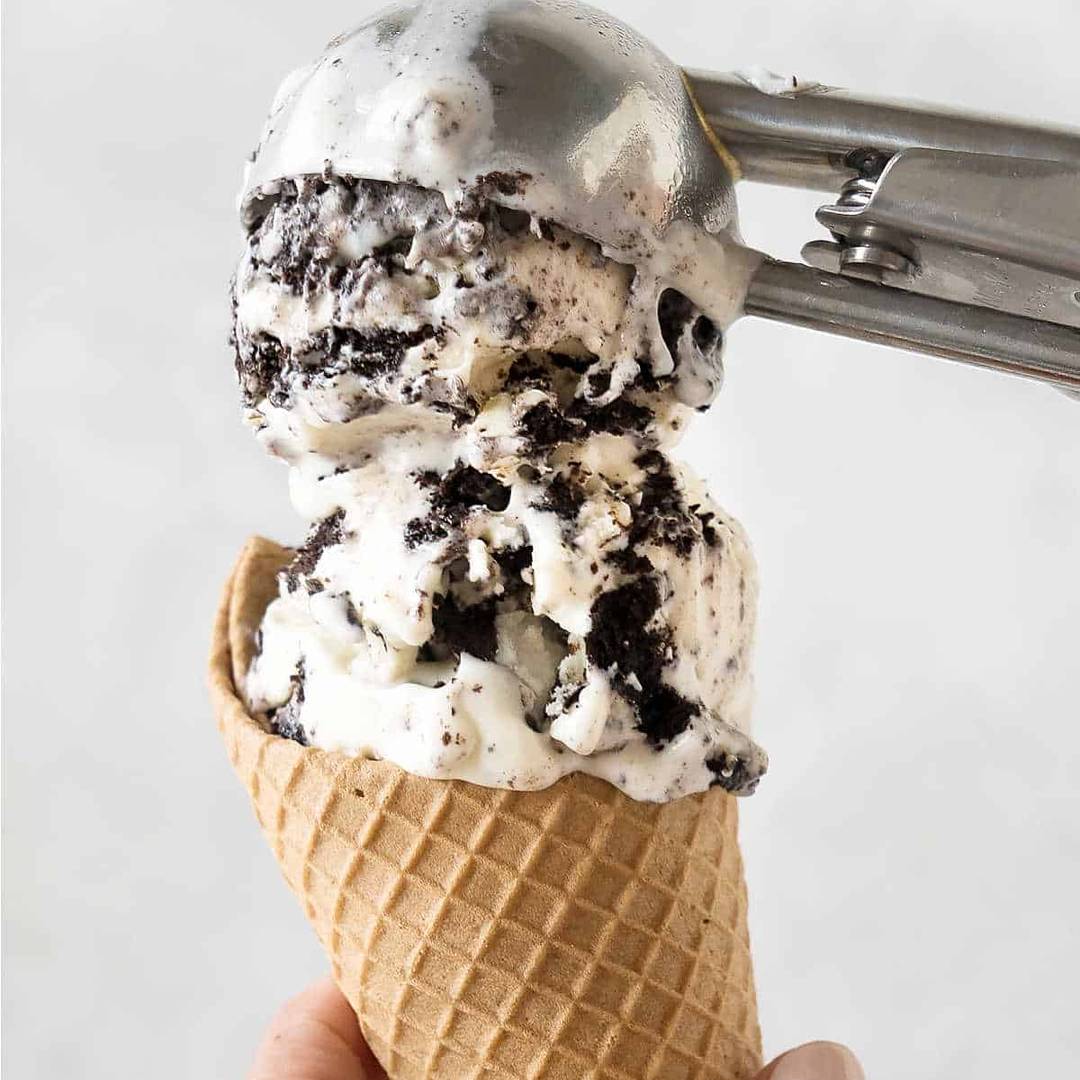 Scooping Oreo ice cream on a waffle cone. 