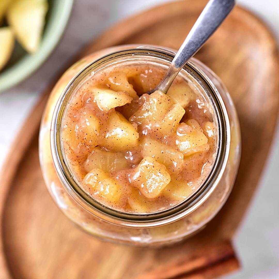Jar of apple pie filling on a wooden board.