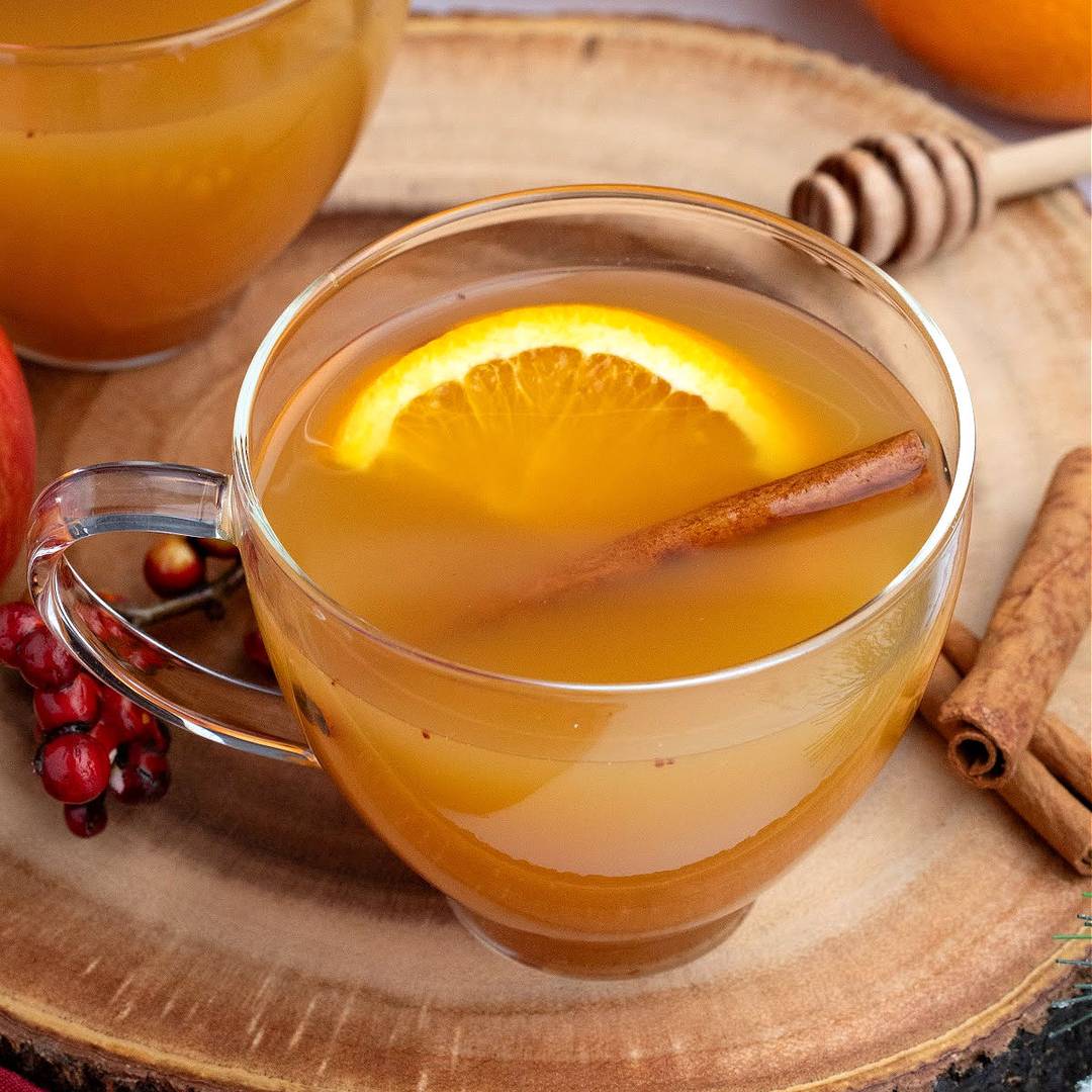 Glass cup with apple cider drink. Orange and cinnamon stick. 