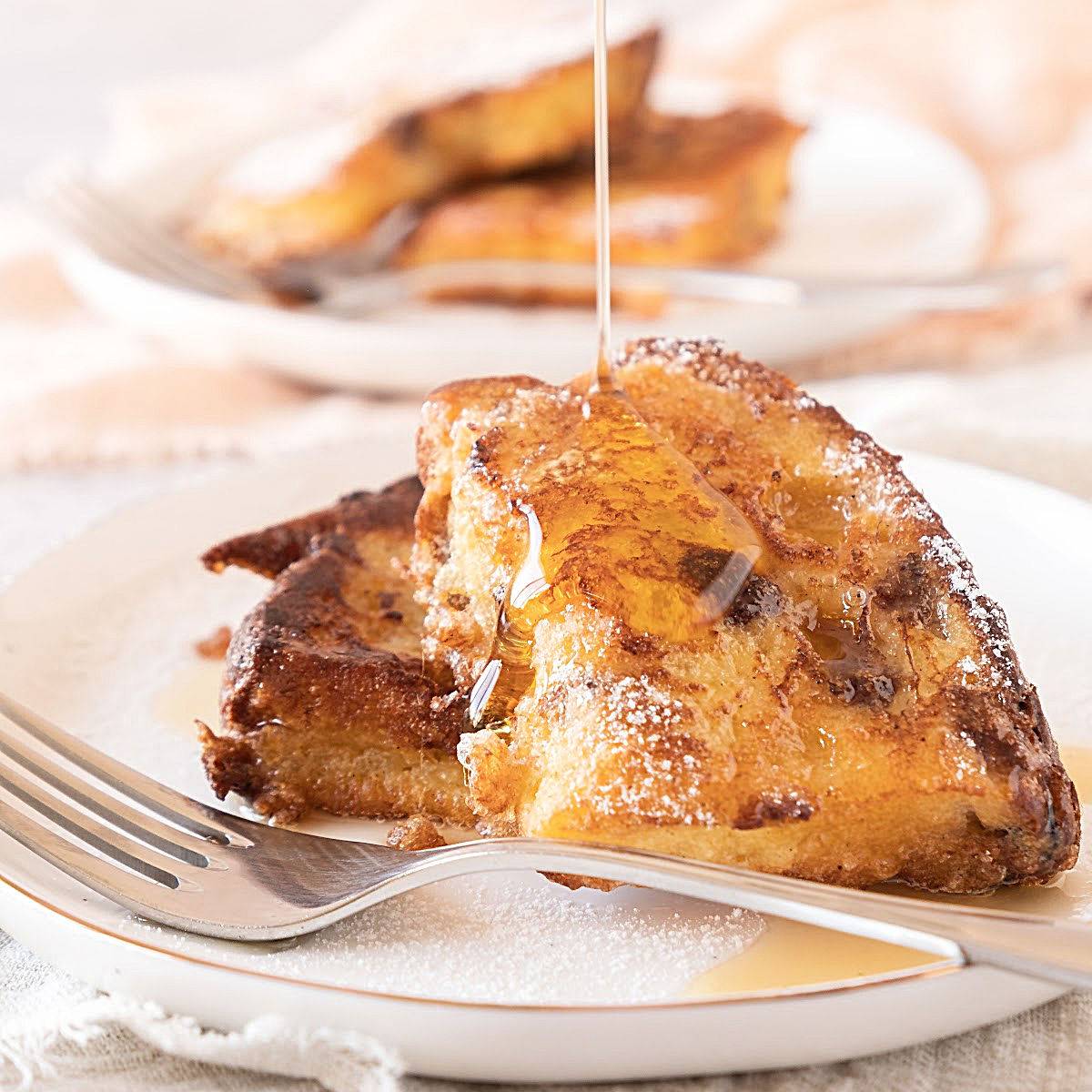 Panettone French toast slices with syrup. White plate and fork.