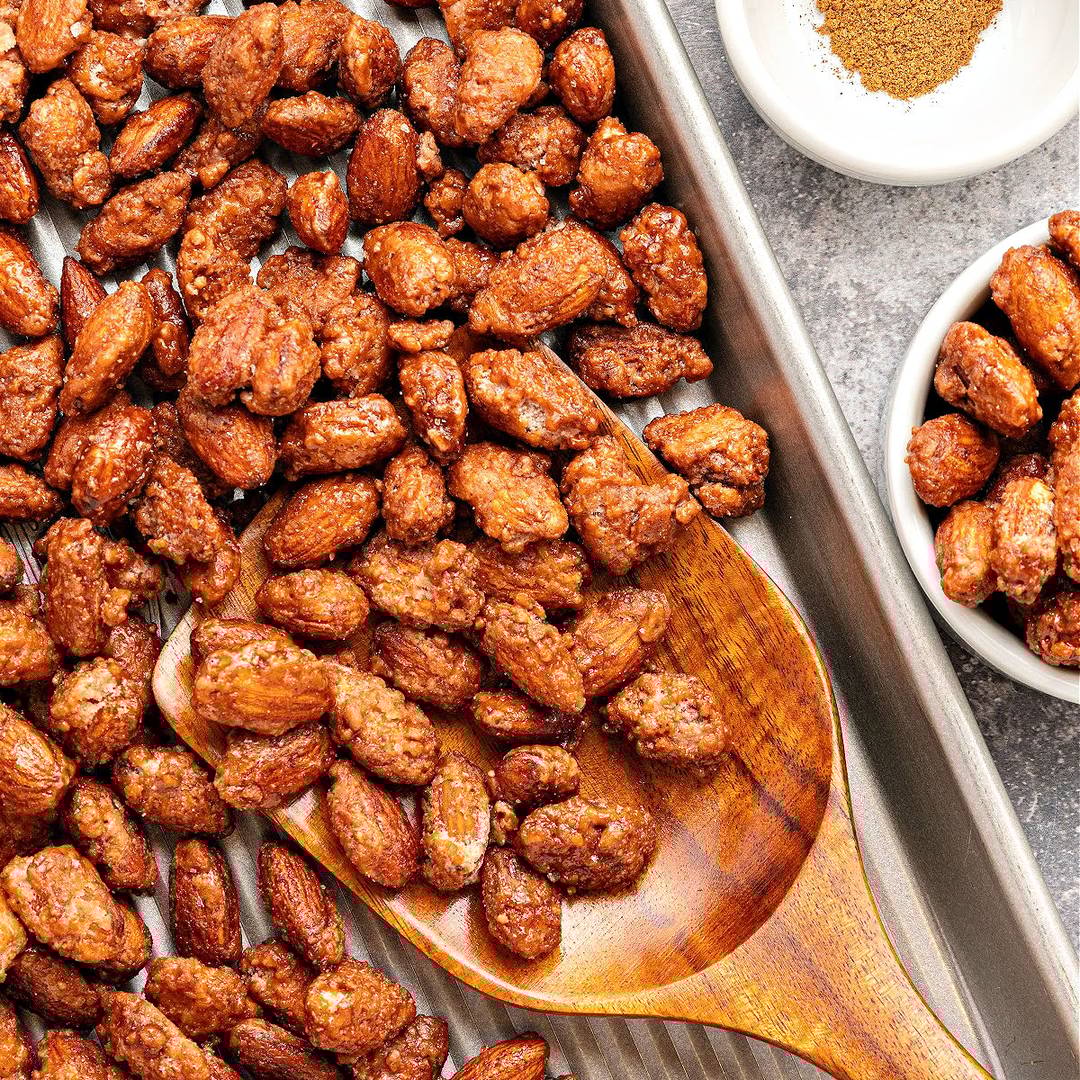 Baking tray with candied almonds. Wooden spoon.