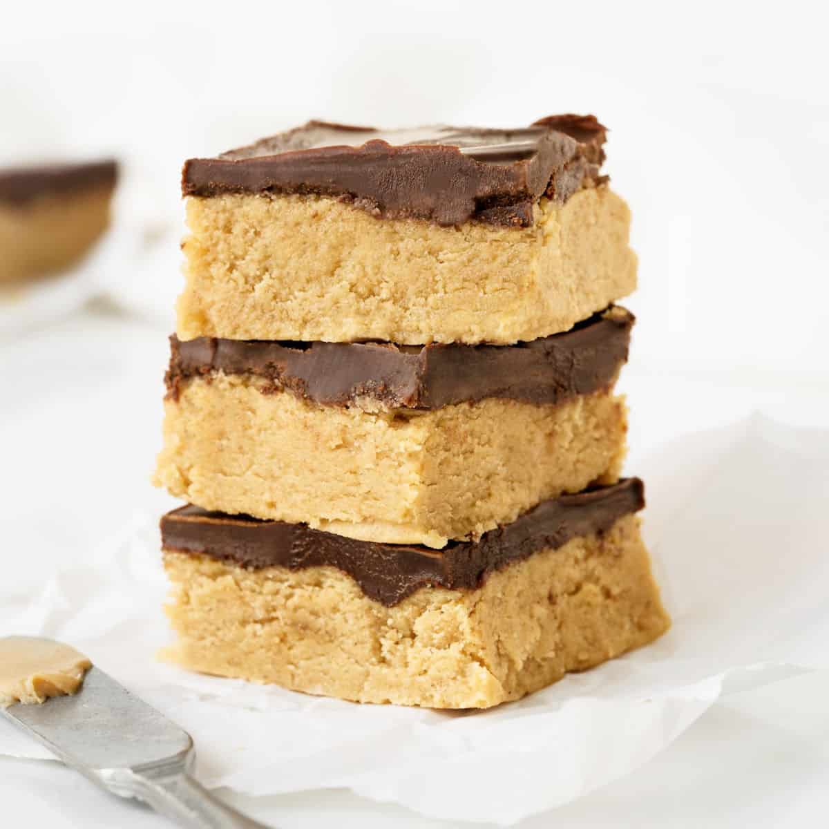 Stack of chocolate-topped peanut butter fudge. White background. 
