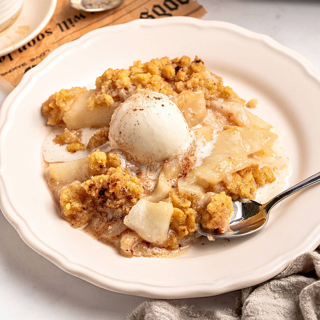 White plate of pear crumble with ice cream. 