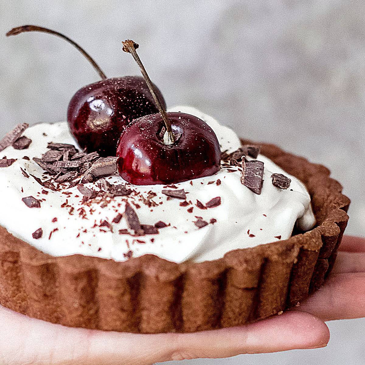 Chocolate cream cherry tart. Gray background.