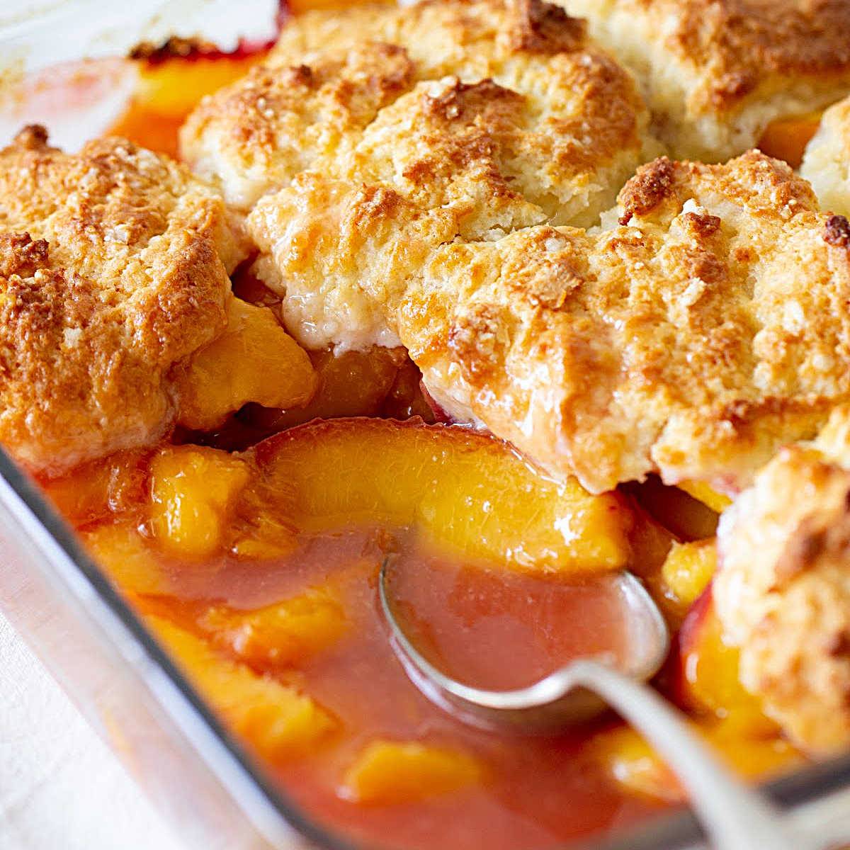 Close up peach cobbler. Silver spoon.