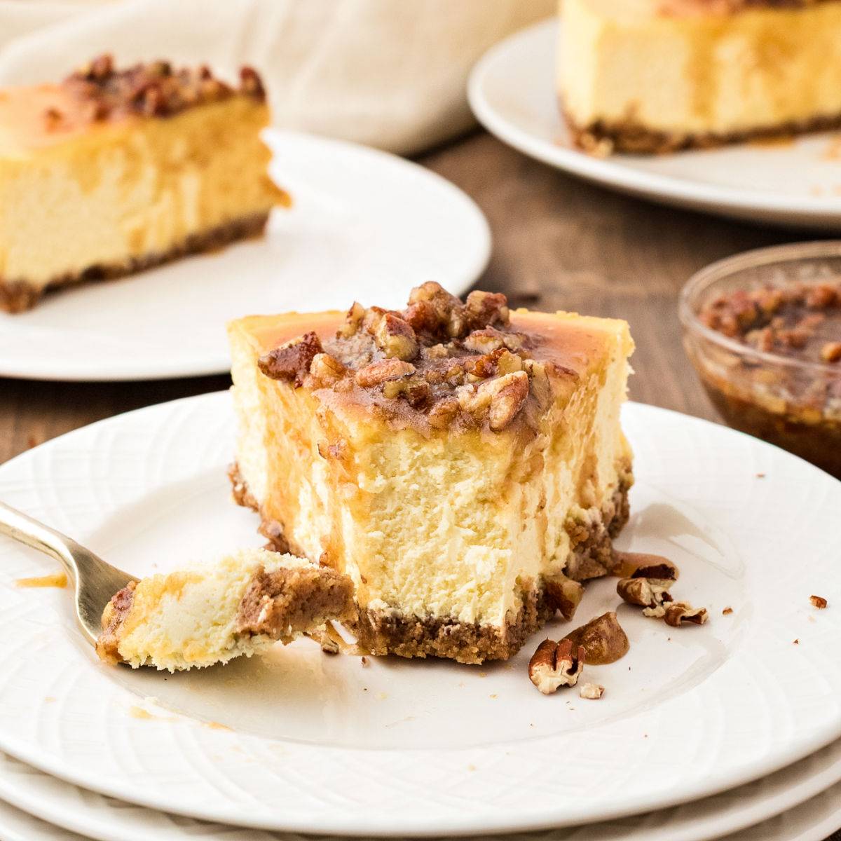 Half eaten slice of pecan maple cheesecake on a white plate. 