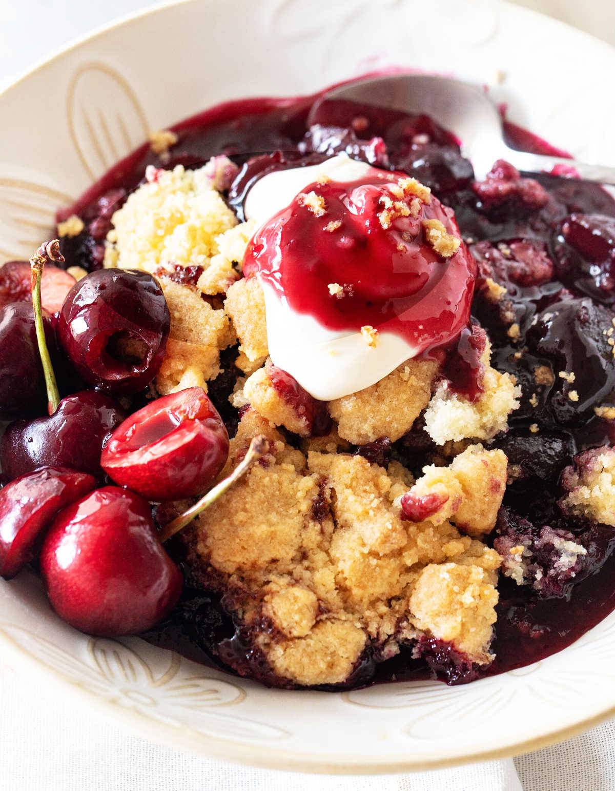 Serving of fresh cherry dump cake with cream. 
