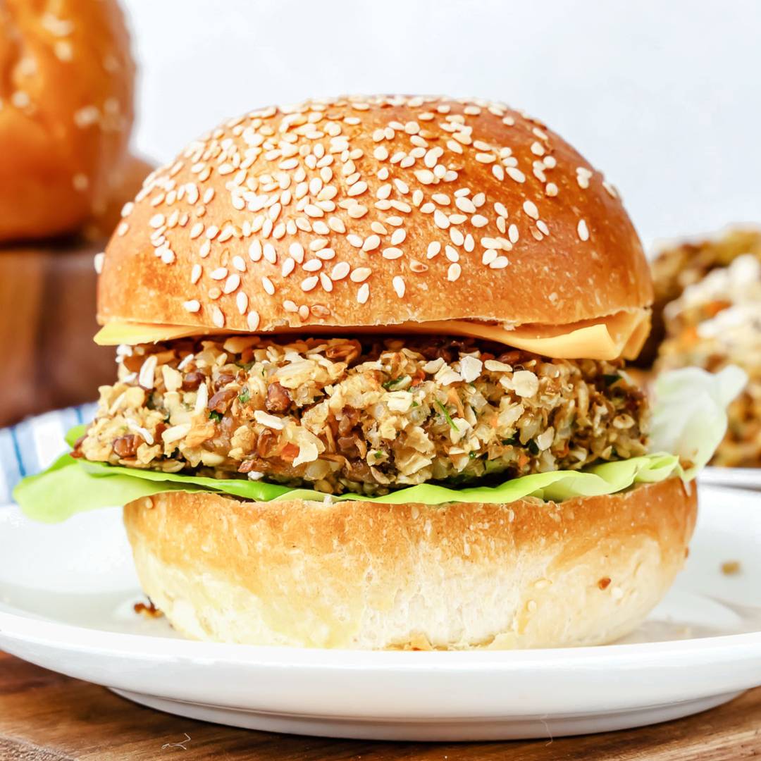 Lentil vegetable burger on sesame bun. White plate.
