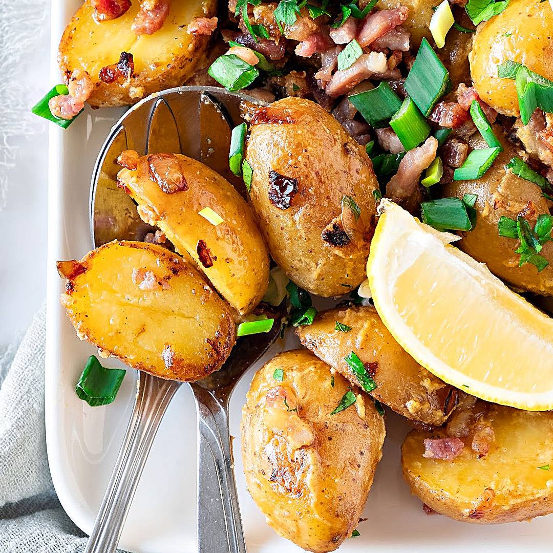 Baby potatoes with bacon and green onions. Lemon wedge.