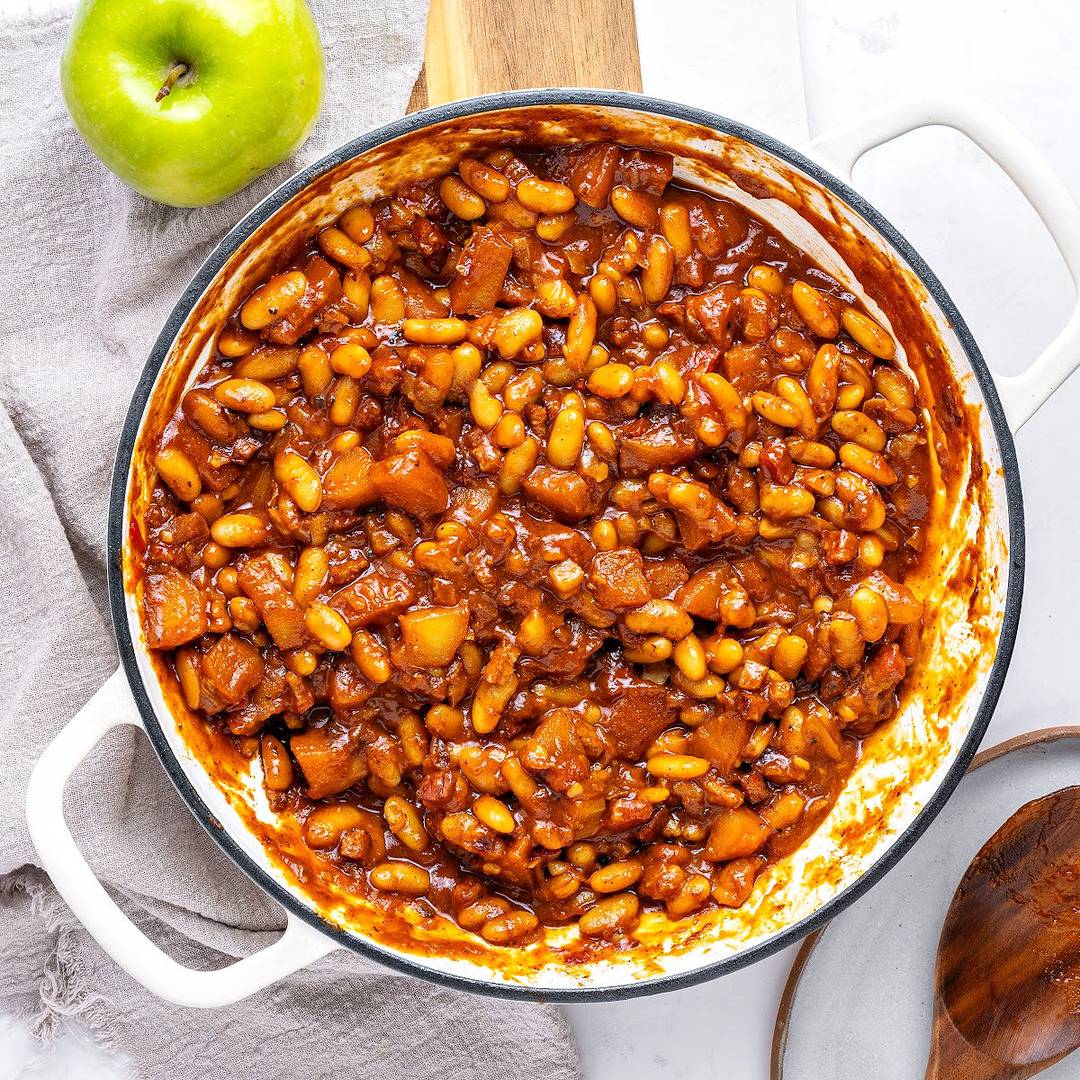 White pot of baked beans and apples.
