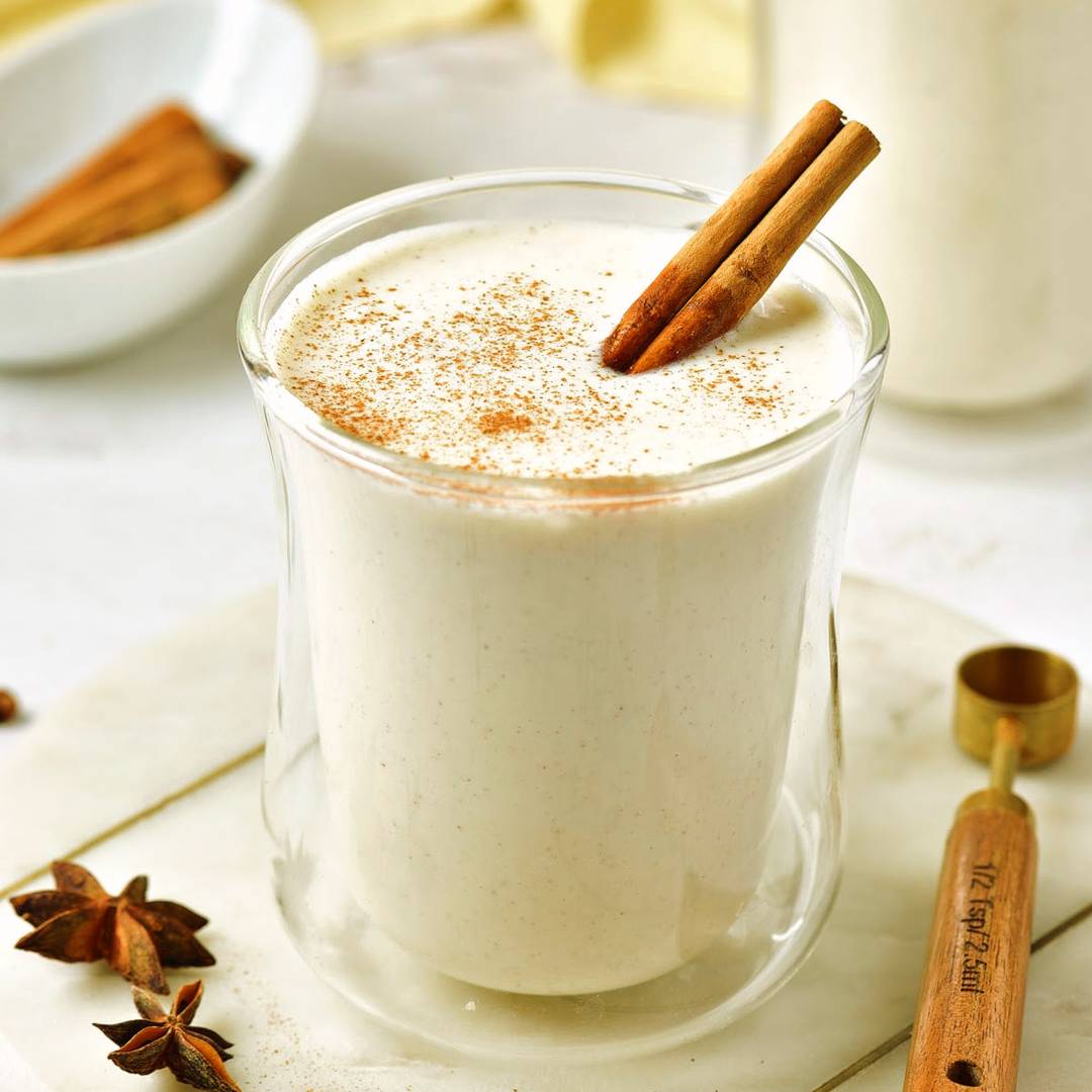 Glass of eggnog with cinnamon stick.