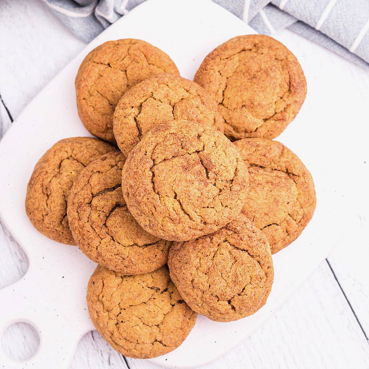Pile of pumpkin cookies on a white plate. 