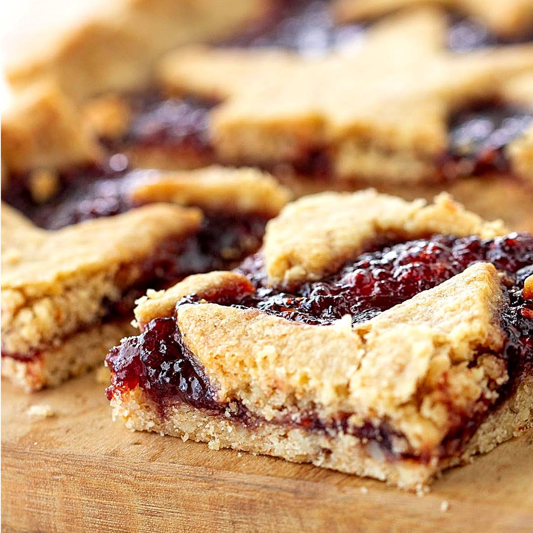Raspberry linzer squares on a wooden board.