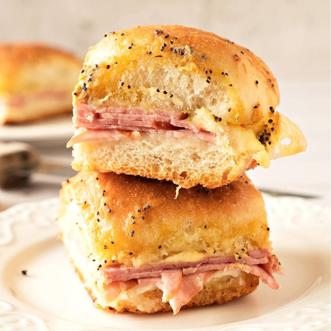Stack of two ham and cheese sliders on a white plate.