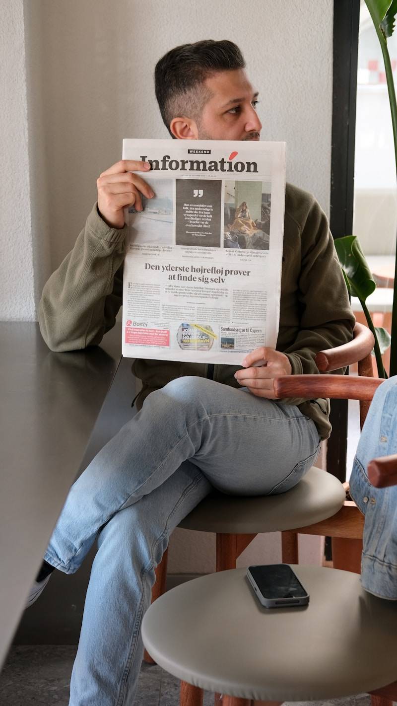 A man sitting in a chair reading a newspaper