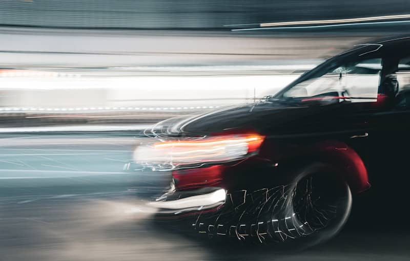 A black car speeds, creating motion blur.