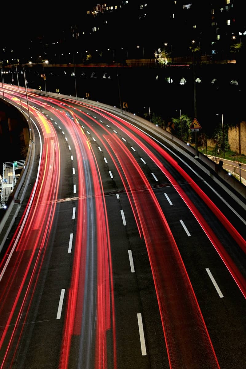 Traffic trails as cars speed down a highway at night.