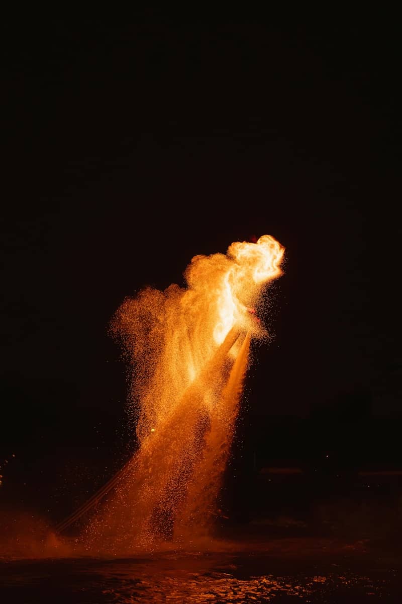 A fiery orange plume erupts into the dark night sky.