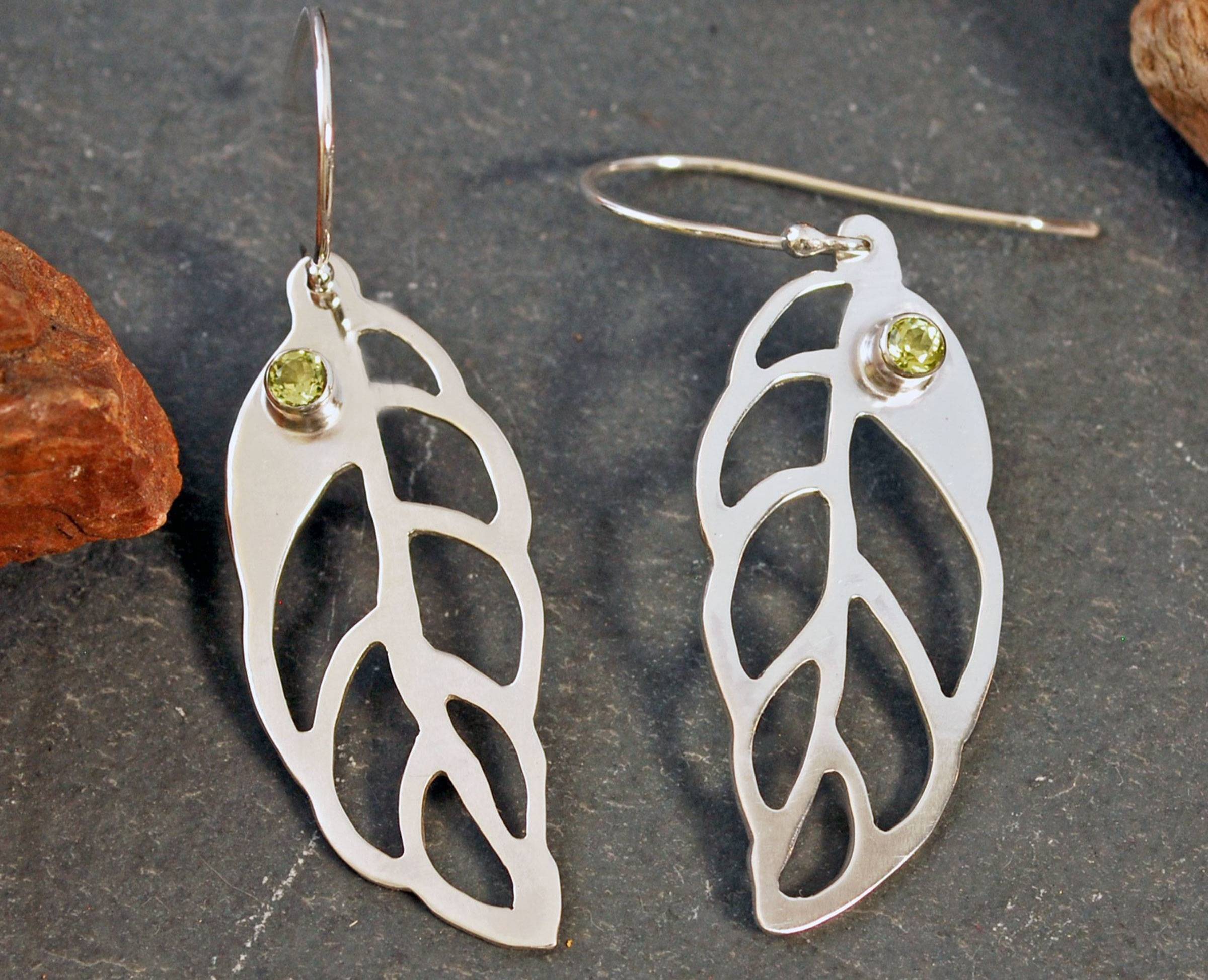 Pair of leaf shaped silver earrings with tube set peridot stones at the top