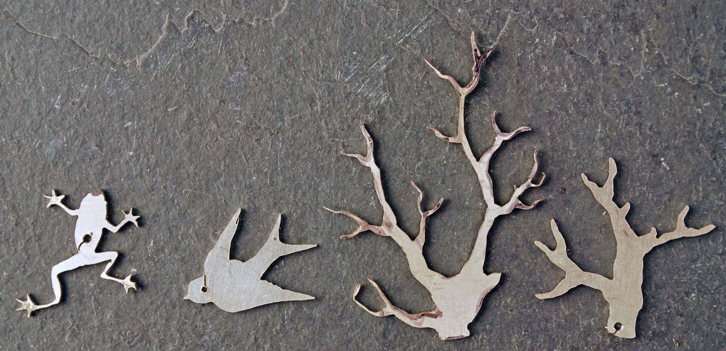 Four cut out pieces: a frog, swallow. two trees