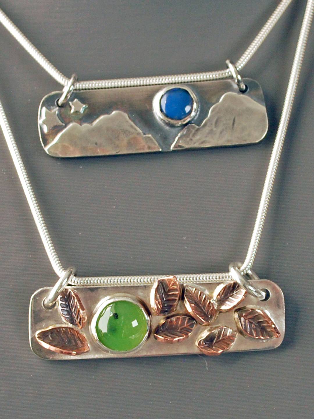 Two horizontal bar pendant, top with mountain scene and opal, bottom one with copper leaves and jade