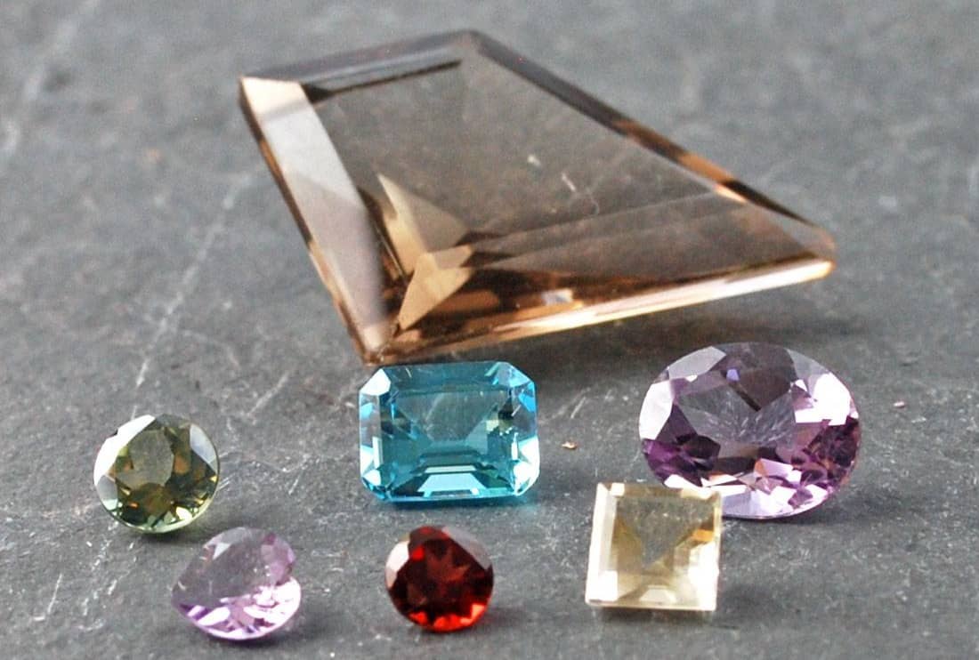 Small group of faceted stones with one large smoky quartz and smaller peridot, topaz, amethyst, garnet, citrine