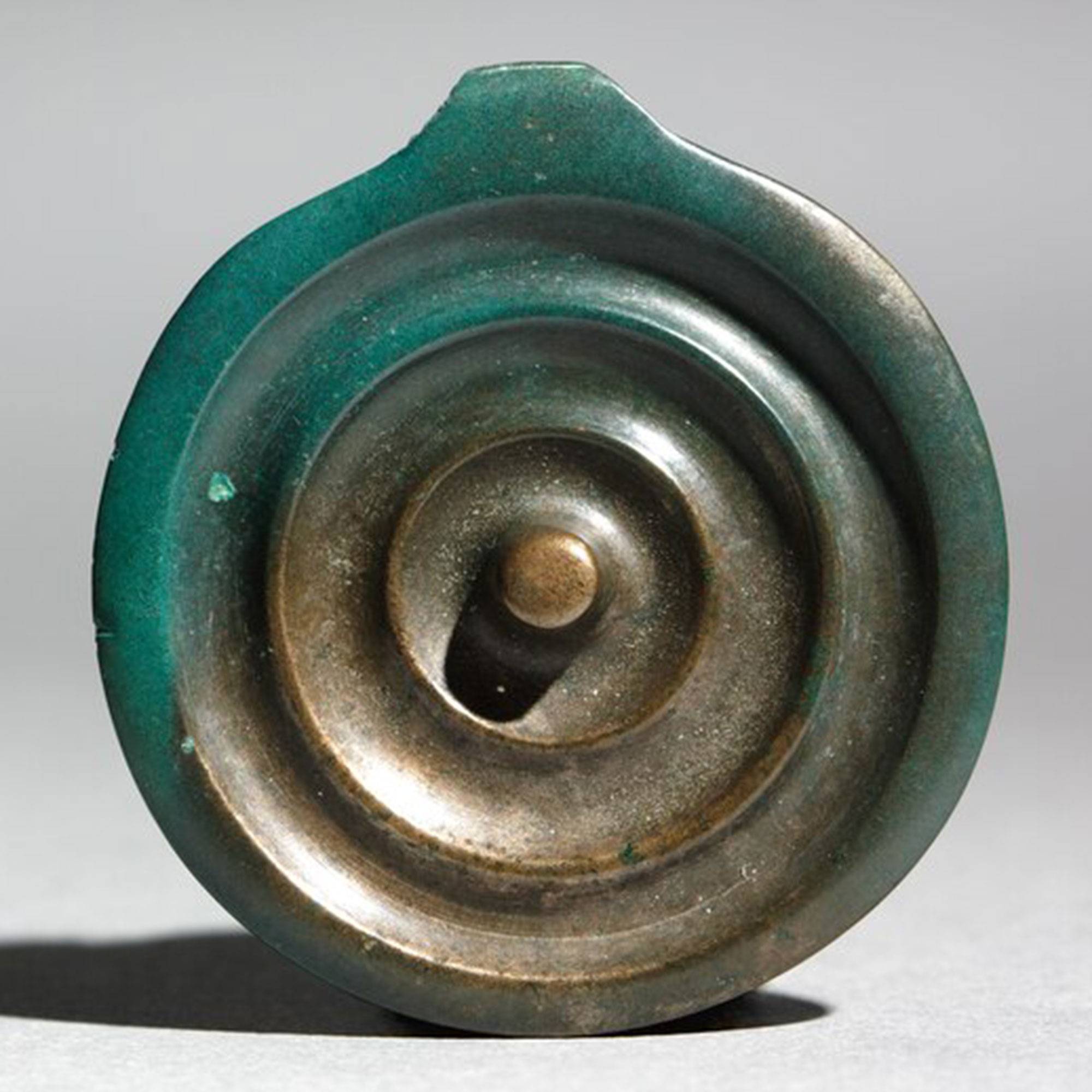 A circular bronze pendant with raised circles inside