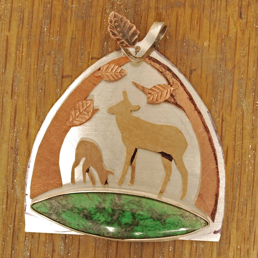 pendant in progress: silver with maw sit sit stone on bottom, bronze deer, copper tree frames