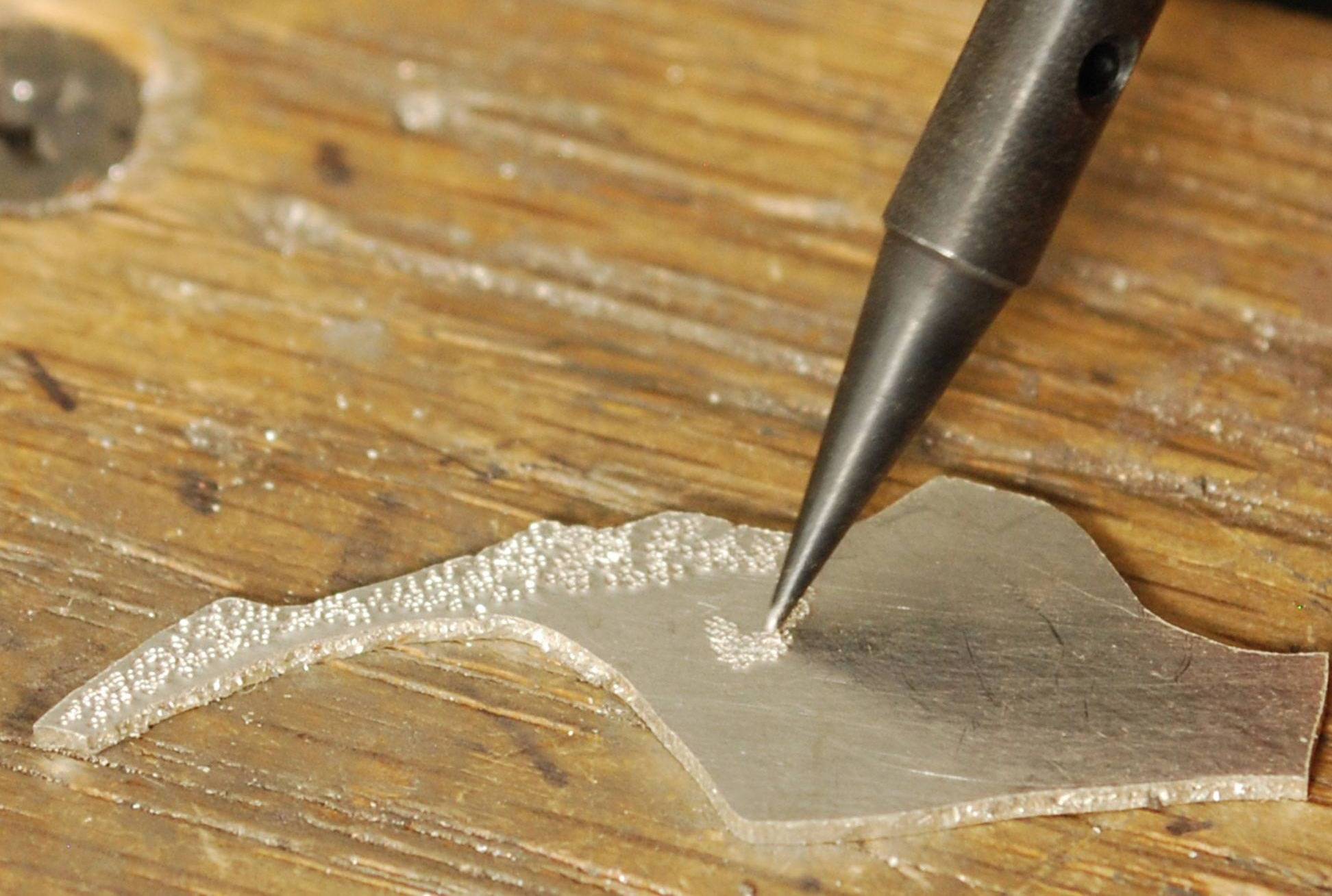 Hammer handpiece pointed tip hammering stippled texture onto a piece of silver