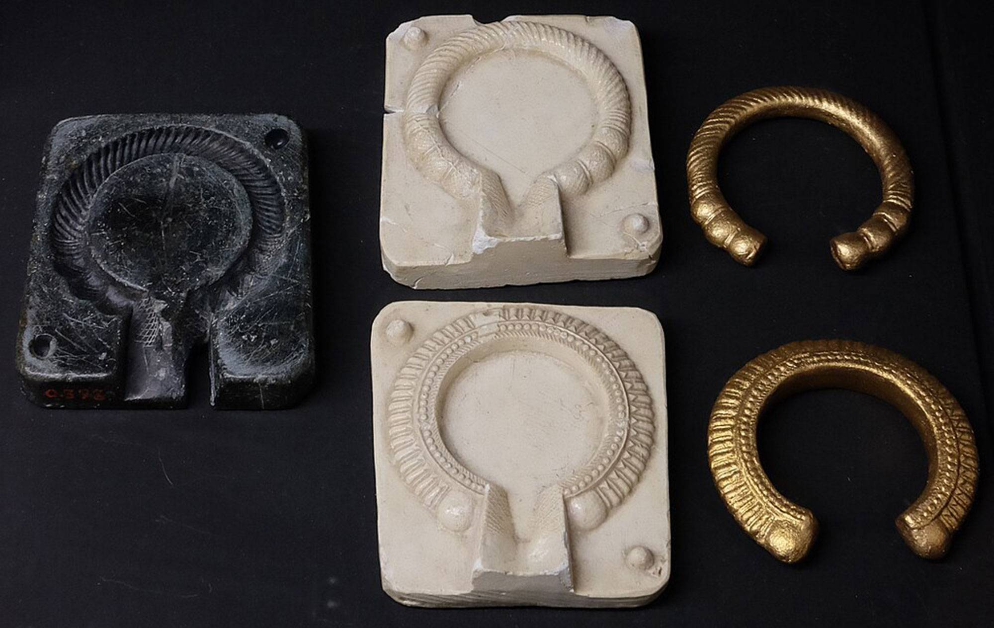 An iron mold, with molded clay impressions and new bronze neck rings made from the mold